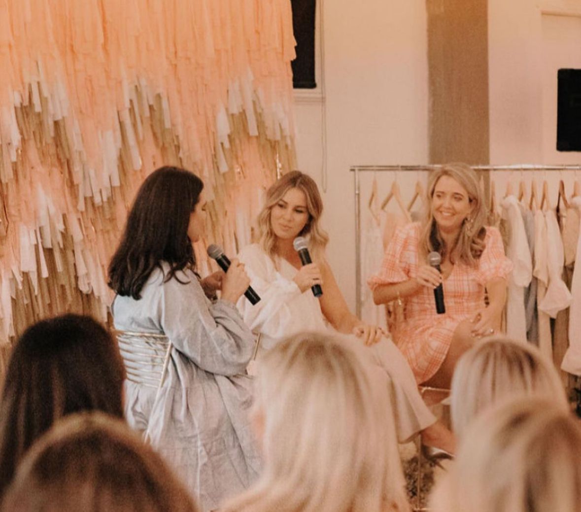 A panel conversation in front of a peach streamer backdrop